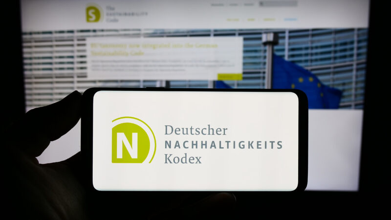 Stuttgart, Germany – 07-11-2023: Person holding smartphone with logo of Deutscher Nachhaltigkeitskodex (DNK) on screen in front of website. Focus on phone display.